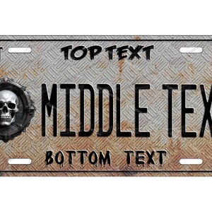 May include: A rusty metal license plate with a skull and crossbones design. The plate has the text "TOP TEXT", "MIDDLE TEXT", and "BOTTOM TEXT" on it. The plate also has the numbers "OCT" and "98" on it.