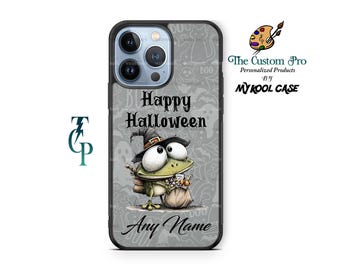 Può includere: Custodia per telefono nera con un design a tema Halloween. Presenta una rana dei cartoni animati con un cappello da strega e una borsa di caramelle. Il testo "Happy Halloween" e "Any Name" è su sfondo grigio con motivi di fantasmi e gatti.