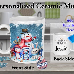 May include: White ceramic mug with a winter scene featuring a snowman, penguins, and a rabbit. The front of the mug has a blue and white watercolor background with snowflakes. The back of the mug is white with the text "Happy Holidays Jessie".