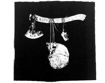 May include: Black and white image of a skull hanging from a wooden branch with two axes hanging from the branch. The skull is hanging from a string.