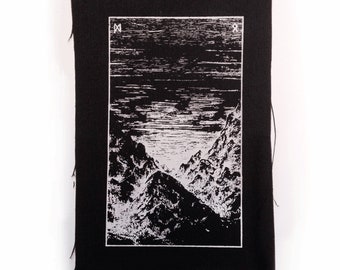 May include: Black rectangular patch with a white graphic of a mountain range and a body of water. The patch has a white border around the graphic and two symbols at the top. The edges of the patch are frayed.