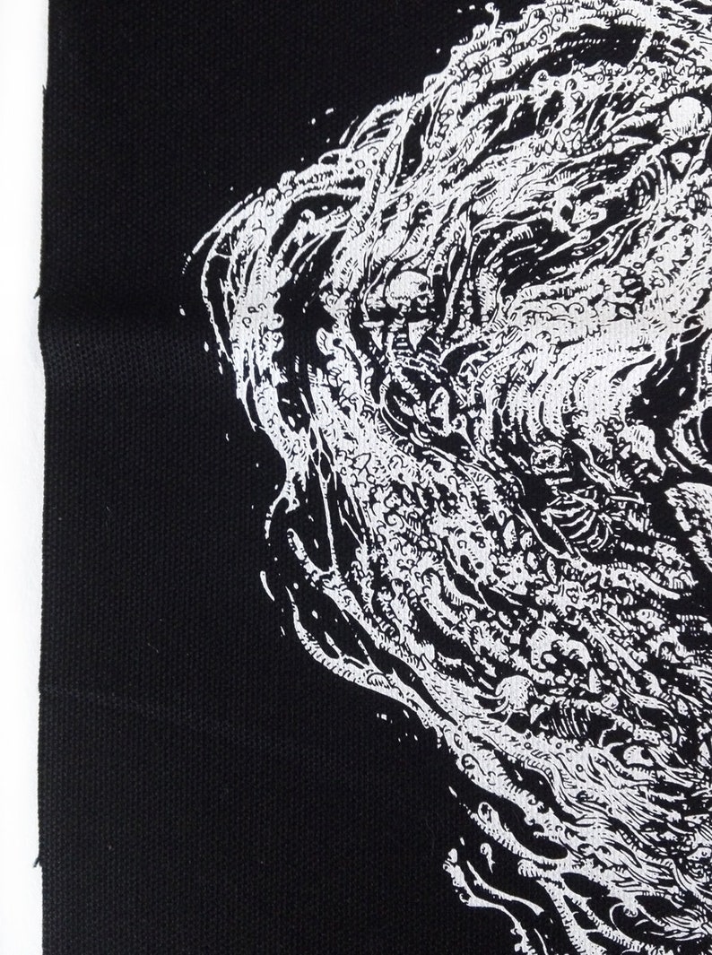 May include: Black fabric with a detailed white illustration. The artwork features a complex, swirling design with organic shapes and a textured appearance. The image is a close-up, highlighting the contrast between the black background and the intricate white design.