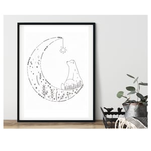 Puede incluir: Ilustraci&oacute;n en blanco y negro de un oso sentado en una luna creciente hecha de flores y hojas. Una estrella cuelga de la parte superior de la luna.
