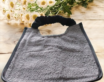 May include: A gray terry cloth shaving bib with a black elastic band around the neck.