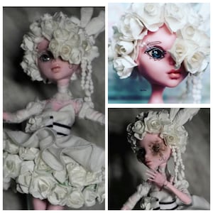 K&ouml;nnte beinhalten: Eine wei&szlig;e Porzellanpuppe mit einer wei&szlig;en Rosenkrone und einem wei&szlig;en Kleid. Die Puppe hat ein bemaltes Gesicht mit blauen Augen und einem schwarzen Augenpflaster. Die Puppe tr&auml;gt ein wei&szlig;es Kleid mit einem schwarzen Streifen um die Taille.