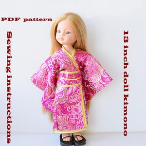 Puede incluir: Patrón PDF e instrucciones de costura para un kimono de muñeca de 33 cm. El kimono es rosa con detalles dorados y un estampado floral.
