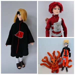 K&ouml;nnte beinhalten: Drei handgefertigte Puppen, inspiriert vom Anime Naruto. Die erste Puppe tr&auml;gt einen schwarzen Umhang mit einem roten Symbol auf der Brust. Die zweite Puppe tr&auml;gt ein rotes Hemd mit einer silbernen Brustplatte. Die dritte Puppe tr&auml;gt einen orangefarbenen Overall und steht neben einem gro&szlig;en orangefarbenen Fuchs.