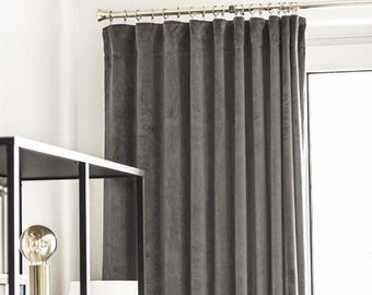 May include: Grey velvet curtains hanging from a metal curtain pole. The curtains are drawn closed and the fabric has a soft, textured look.