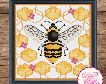 May include: A square cross-stitch pattern in a black frame featuring a central yellow and black bee surrounded by yellow hexagonal honeycomb shapes and small pink flowers. The design is set against a white background with an orange border.