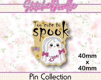 May include: A 40mm by 40mm pin featuring a white ghost with pink bows and a purple spider. The text reads Too cute to spook and Boo. The design includes small gold stars on a light wood-toned background, presented as part of a StitcheDoodle pin collection.