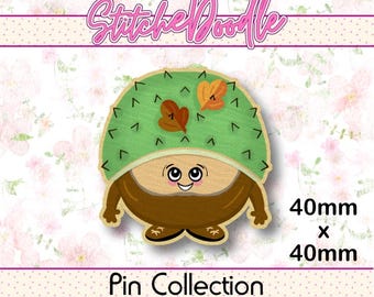 May include: A StitcheDoodle pin collection item measuring 40mm x 40mm. The pin features a cartoon character with a light green, spiky, chestnut-shaped hat adorned with two orange leaves, a tan face with large eyes, and a brown body with small feet.