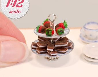 May include: A miniature two-tiered serving stand featuring a 1:12 scale label. The top tier holds chocolate-dipped strawberries, while the bottom tier is filled with small rectangular chocolate sandwich cookies with a white cream filling.