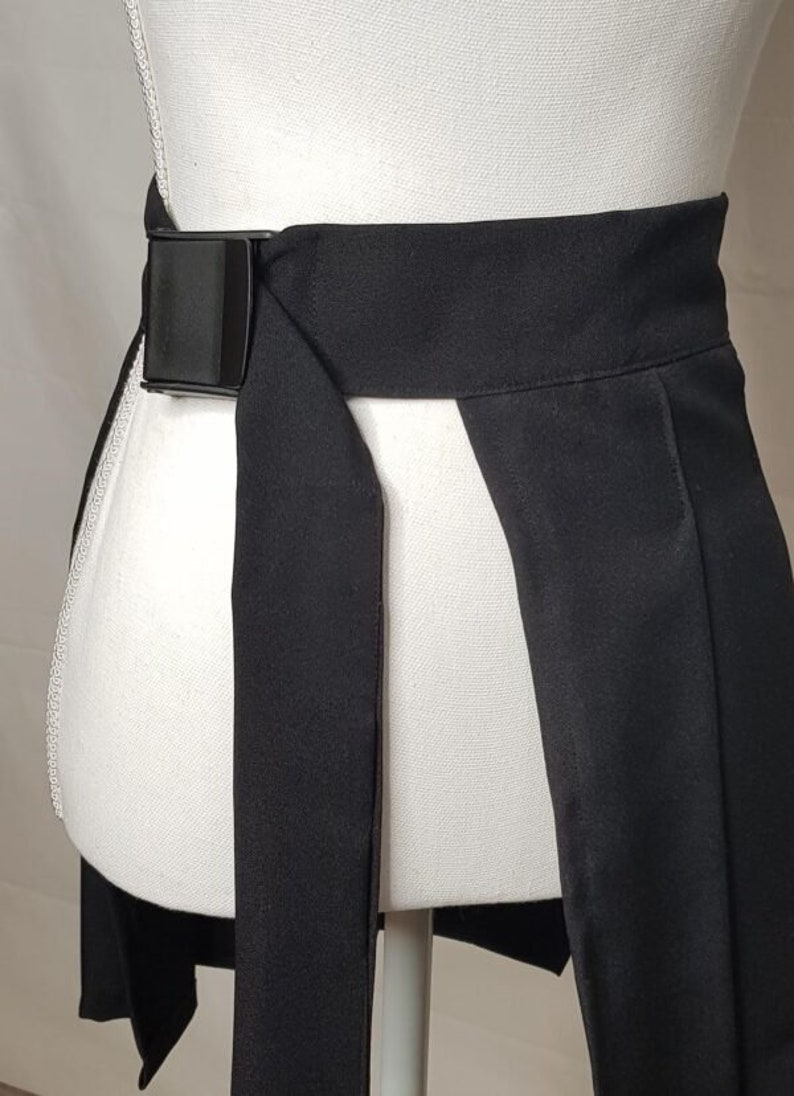 May include: A black wrap skirt with a black adjustable buckle belt. The skirt has a front slit and is made of a smooth fabric.