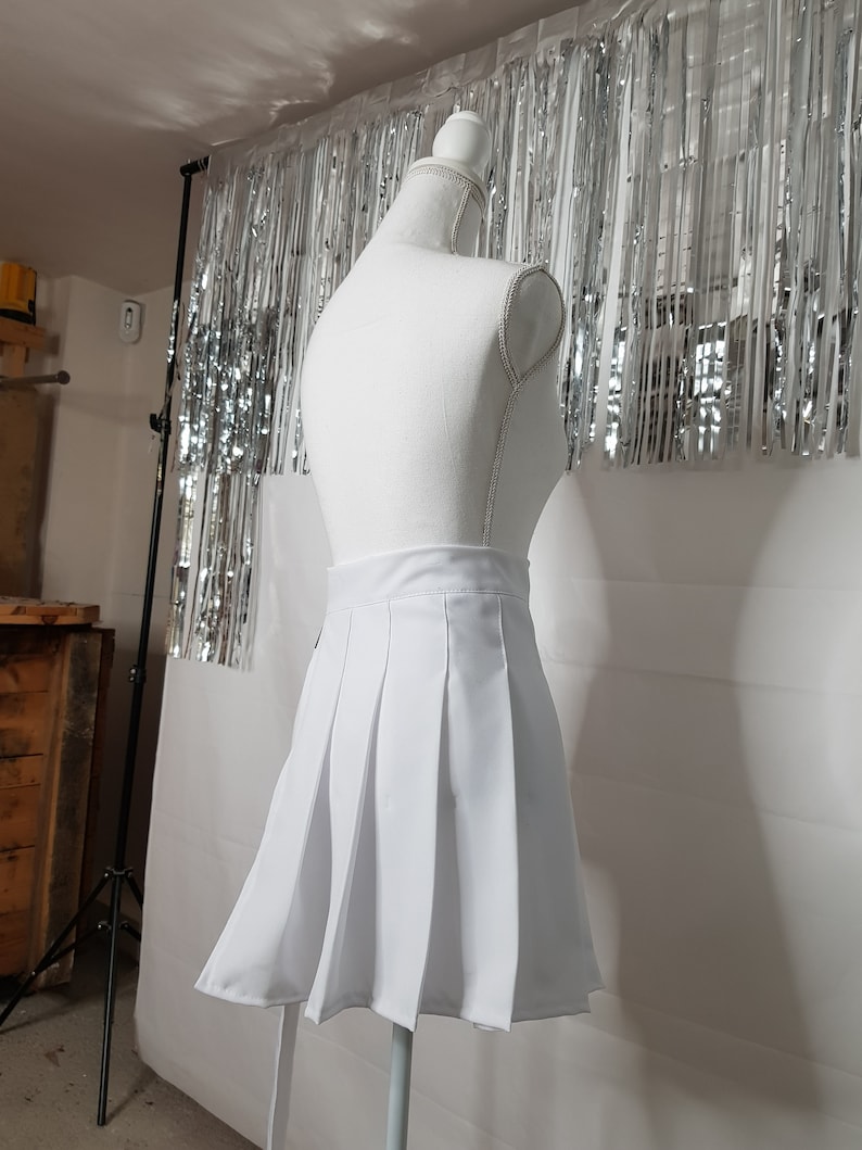 May include: A white pleated skirt on a white mannequin. The skirt is short and has a high waist.