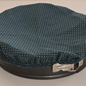 Può includere: Una tortiera blu scuro con una copertura in tessuto abbinata. La copertura è decorata con piccoli pois bianchi. La tortiera ha una chiusura in metallo ed è progettata per la cottura.