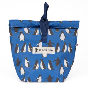 May include: A blue reusable lunch bag with a penguin pattern and a navy blue drawstring. The bag has a white label with the text "is cool man".