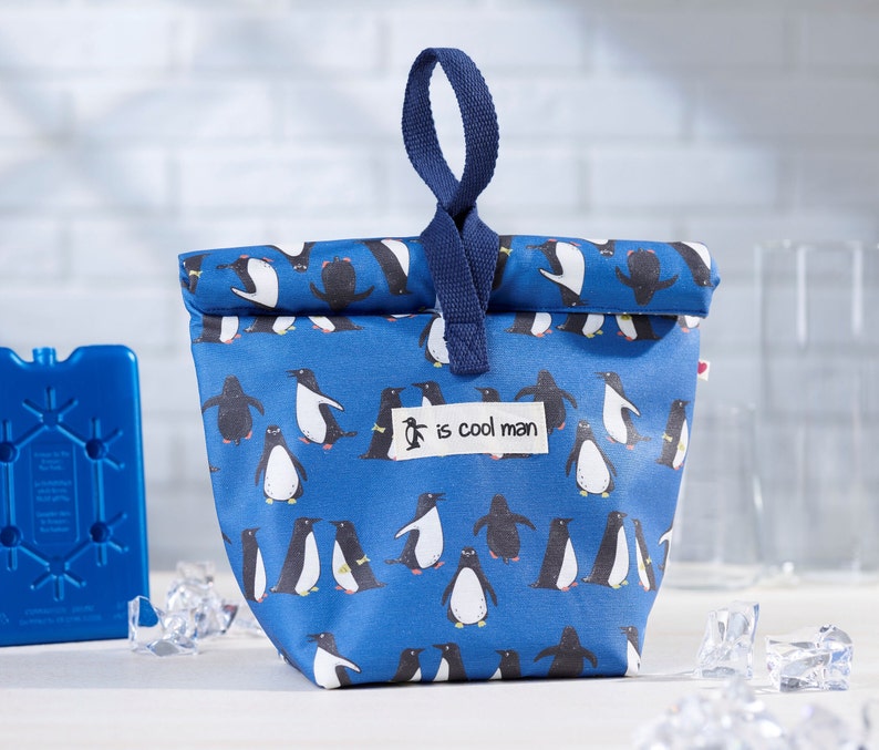 May include: Blue lunch bag with a penguin pattern and the text "is cool man".