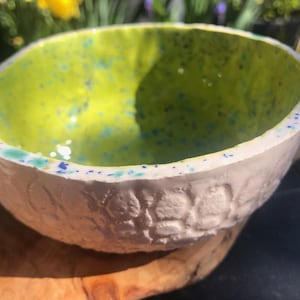 May include: A white ceramic bowl with a textured exterior and a bright green interior with blue speckles.