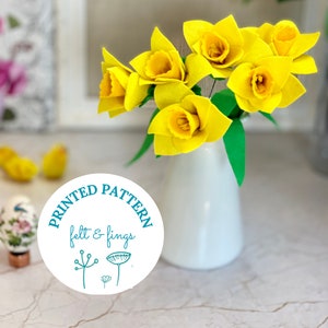 May include: A printed pattern for felt and fring crafts featuring a bouquet of yellow felt daffodils in a white vase. The pattern is labeled "Printed Pattern felt & fring"