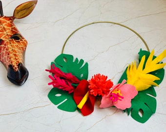 May include: A gold metal wreath decorated with felt flowers and leaves. The flowers are pink, red, and yellow, and the leaves are green.