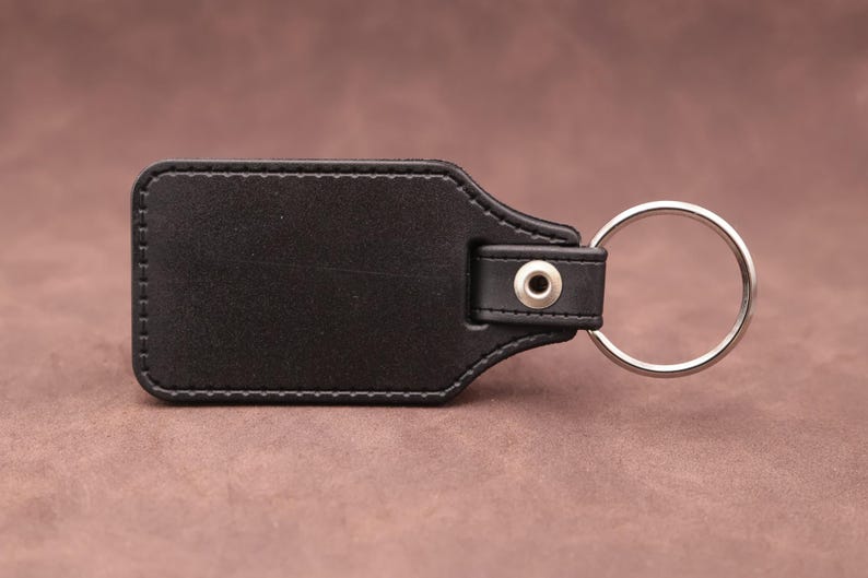 Rear of the medallion keyring with black leatherette fob on a brown suede background.
