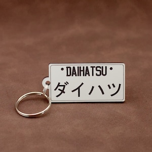 May include: White keychain with a black rectangular tag that says "DAIHATSU" and "ダイハツ" in Japanese characters.