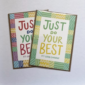May include: Two rectangular greeting cards in clear plastic sleeves. The front card features the text "JUST DO YOUR BEST IT'S GOOD ENOUGH!" in green and yellow, framed by a colourful border of squares with wavy, zigzag, and striped patterns.