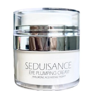 Może przedstawiać: Srebrny i biały słoiczek z kremem pod oczy z napisem "Seduisance Eye Plumping Cream Hyaluronic Acid Intense Therapy" z przodu.