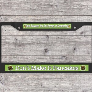 May include: Black license plate frame with green and white text that reads "Just Because You Put Syrup on Something" and "Don't Make It Pancakes". The frame has a pancake graphic.