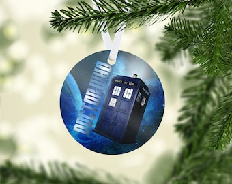 May include: Round Christmas ornament featuring the iconic blue police box from Doctor Who, set against a cosmic background. The words "DOCTOR WHO" are printed in a stylized font. The ornament hangs from a white ribbon.
