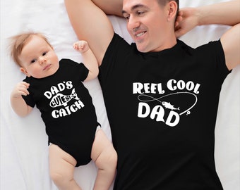 May include: A black t-shirt with the text "Reel Cool Dad" and a fishing hook with a fish on it. A black onesie with the text "Dad's Cutest Catch" and a fish on it.