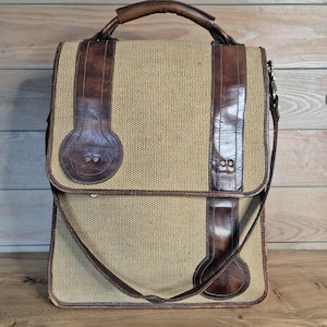 Peut inclure: Sacoche rectangulaire avec un corps en toile beige et des détails en cuir marron. Le sac est doté d'une poignée supérieure, d'une bandoulière et d'une fermeture à rabat. Les lanières et les détails en cuir lui donnent un aspect vintage.