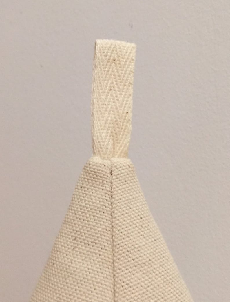 May include: A cream-coloured canvas bag with a cream-coloured fabric handle. The bag is made of a tightly woven fabric.
