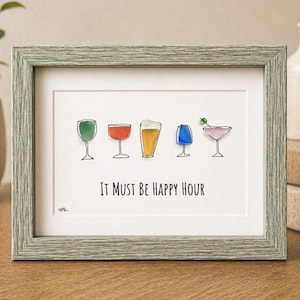 Könnte beinhalten: Ein gerahmtes Wandbild mit fünf farbenfrohen Glas-Illustrationen, darunter ein grünes Weinglas, ein roter Cocktail, ein Bierglas, ein blaues Glas und ein rosa Martini mit Olive. Der Text lautet, It Must Be Happy Hour.