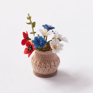 May include: A small crocheted flower arrangement in a brown pot. The flowers are white, red, and blue.