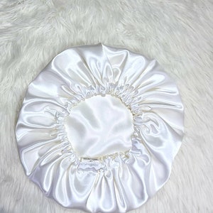 May include: White satin sleep cap with a gathered elastic band. The cap is designed to protect hair while sleeping.