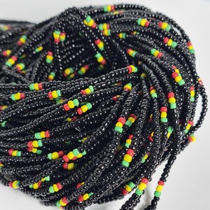 May include: A close-up of a black beaded necklace with red, yellow, and green accents. The beads are small and tightly woven together, creating a smooth and elegant look.
