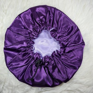 Puede incluir: Una gorro de dormir de satén morado con cierre de cordón. El gorro está diseñado para proteger el cabello mientras duermes.