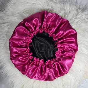 Puede incluir: Una gorro de dormir de satén rosa con forro de satén negro. El gorro está diseñado para proteger el cabello mientras duermes.