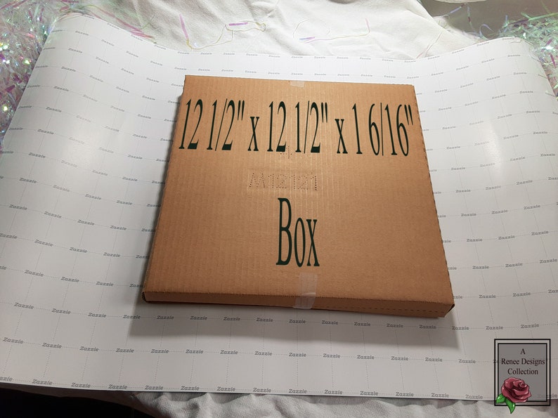 May include: A brown cardboard box with the text "12 1/2" x 12 1/2" x 1 6/16" Box" printed on the front.