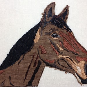 May include: Embroidered brown horse head with black mane against a white background.