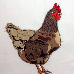 Könnte beinhalten: Ein gesticktes Huhn in Braun- und Beigetönen mit einem roten Kamm und roten Kehllappen. Das Huhn steht auf einem weißen Hintergrund.