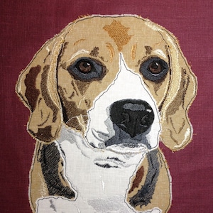 May include: Embroidered image of a beagle dog's head with brown, white and black fur. The dog is looking directly at the viewer with a serious expression.