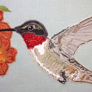 May include: Embroidered image of a hummingbird with a red throat, perched on a branch with orange flowers. The hummingbird is in flight with its wings spread out.