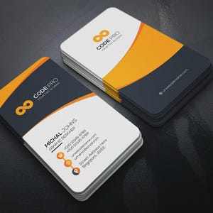 May include: A stack of rectangular business cards with rounded corners featuring a white, dark grey, and orange colour scheme. The cards display the text CODE PRO, a graphic infinity symbol, and contact details for a graphic designer named Michal Johns.