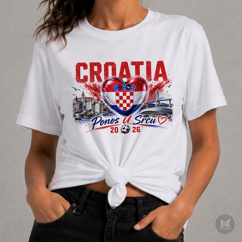 Może przedstawiać: Biały t-shirt z kr&oacute;tkim rękawem z grafiką przedstawiającą napis CROATIA, chorwacką flagę w kształcie serca, ilustrację miasta nadmorskiego, most oraz napis Ponos U Srcu 20 26 z ikoną piłki nożnej umieszczoną na dole pośrodku.