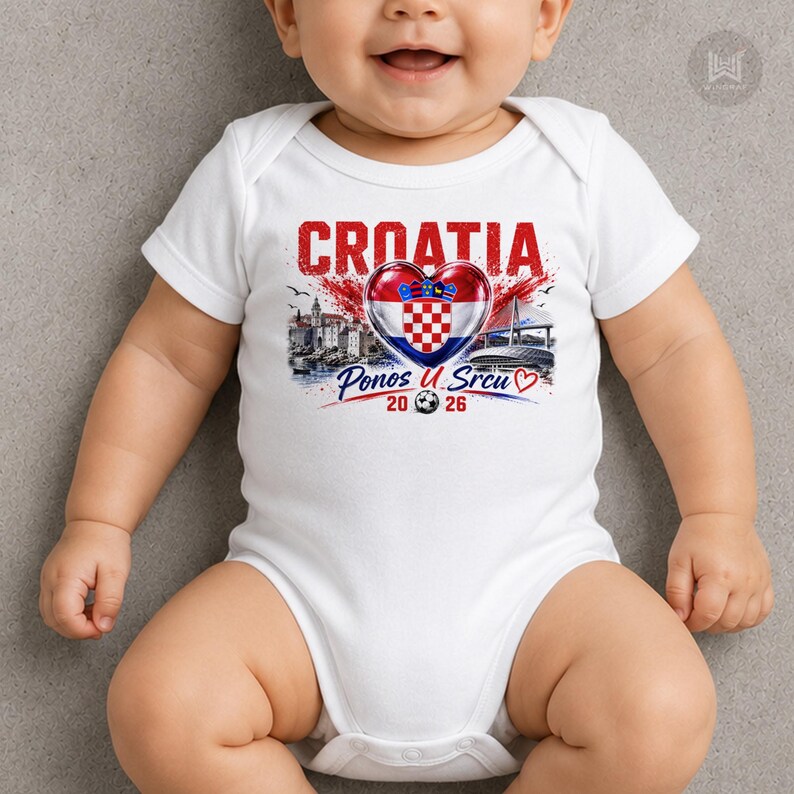 Może przedstawiać: Białe body niemowlęce z kr&oacute;tkim rękawem z nadrukiem graficznym zawierającym napis CROATIA nad chorwacką flagą w kształcie serca. Poniżej serca znajduje się napis Ponos U Srcu 20 26 z ikoną piłki nożnej oraz czerwonym konturem serca.