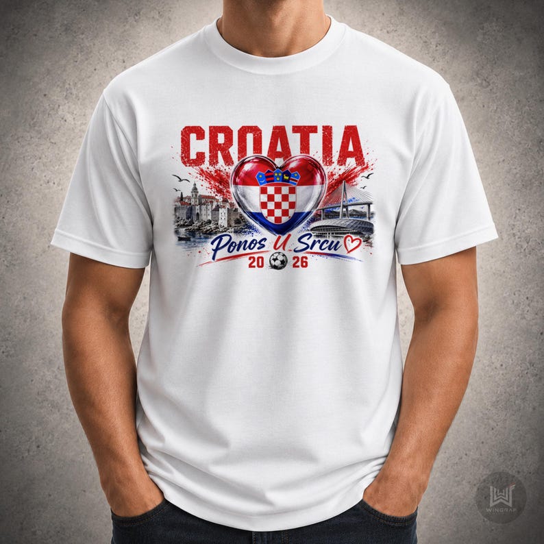 Może przedstawiać: Biały t-shirt z kr&oacute;tkim rękawem z nadrukiem graficznym zawierającym czerwony napis CROATIA, chorwacką flagę w kształcie serca, ilustrację miasta nadmorskiego, most oraz napis Ponos U Srcu 2026 z małą ikoną piłki nożnej.