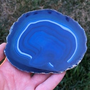 May include: A blue agate slice with white banding. The agate is polished and has a smooth surface.