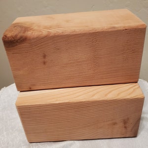 May include: Two natural wood blocks stacked on top of each other. The blocks are made of light brown wood with a smooth finish.